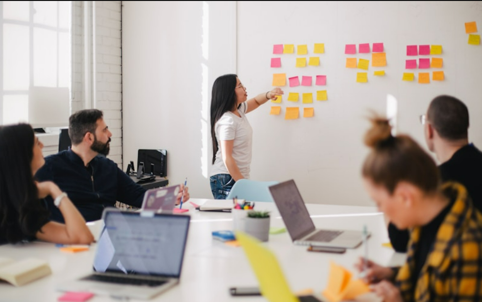 Diverse business team planning AI strategy with whiteboards and digital presentations